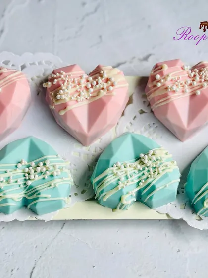 These geometric heart treats are a unique addition to a gender reveal party. Coated in pink and blue chocolate with a white chocolate drizzle, they can be filled with a surprise color inside.