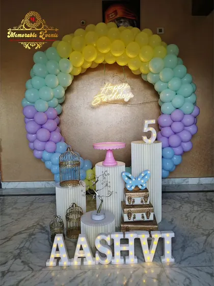 A pastel rainbow-colored balloon ring for a 5th birthday celebration.