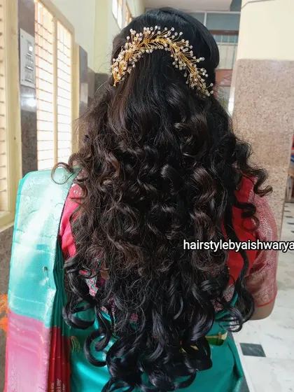 A gorgeous hairstyle with voluminous curls, perfect for a naming ceremony or any festive occasion. The half-up style is adorned with a beautiful gold and pearl hair accessory.