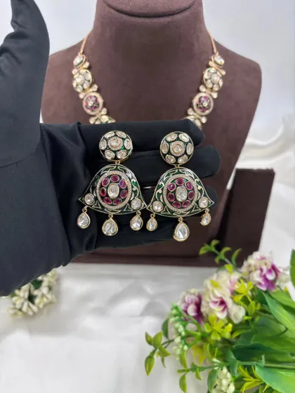 A unique necklace with a pendant featuring green and red Meenakari work, perfect for adding a pop of color.