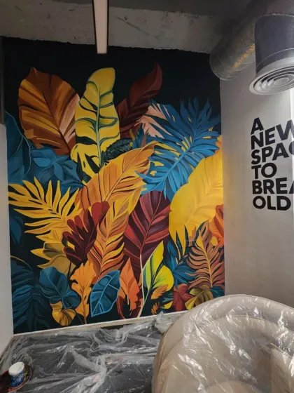 The completed botanical mural next to a typography piece that reads "A NEW SPACE TO BREAK OLD RULES." This combination of art and text creates a powerful, motivating atmosphere in the office.