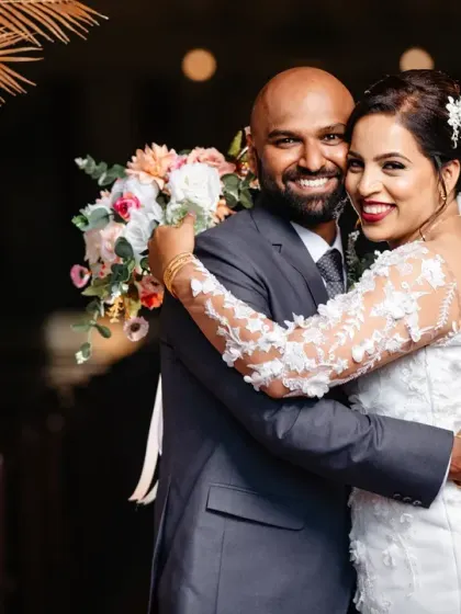 A happy, relaxed portrait of the bride and groom. Their comfortable embrace and genuine smiles show the easy joy of being newly married.