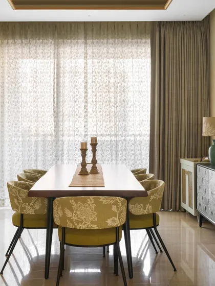 A closer look at the dining area in the Ivy Nest, with chartreuse floral chairs and a simple, elegant table setting. The sheer curtains diffuse the natural light beautifully.