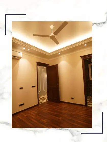 A bedroom should be a place to elevate your lifestyle. This space features rich wooden flooring, a false ceiling with concealed lighting, and a view into a hallway with classic patterned tiles.