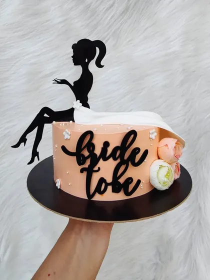 An elegant silhouette cake for a bridal shower. The design features a bride-to-be sitting atop the cake, with a flowing fondant dress.