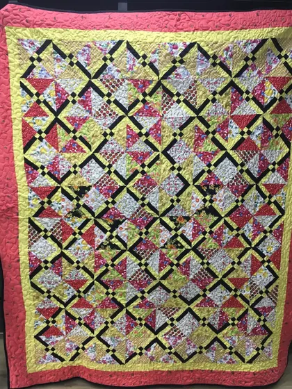 A complex and colorful scrappy quilt with a "pinwheel and star" combination pattern.