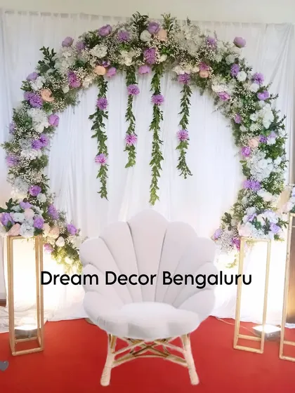 A beautiful backdrop for any occasion, using artificial flowers and baby's breath. The full floral arch and the stylish shell-shaped chair create a chic and photogenic spot.