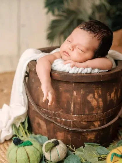 This relaxed pose in a rustic bucket is adorable. The soft white blanket draped over the side adds a nice textural contrast to the dark wood.