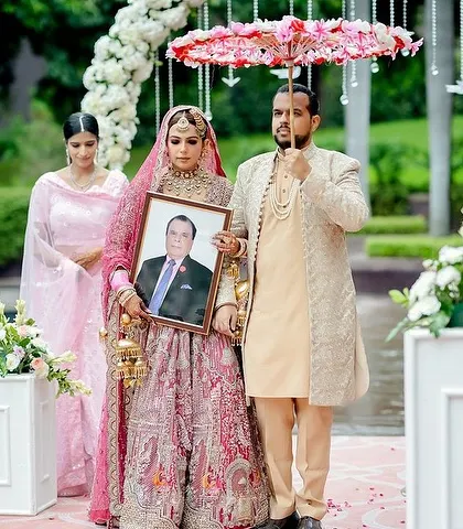 A touching moment during the bridal entry. Even in wider shots, the bride's mehandi is a visible and important part of her ceremonial look.