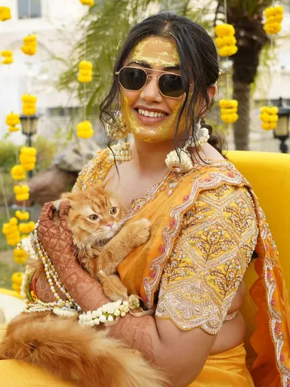 A fun and unique moment as the bride, with Haldi on her face, poses with her adorable cat.
