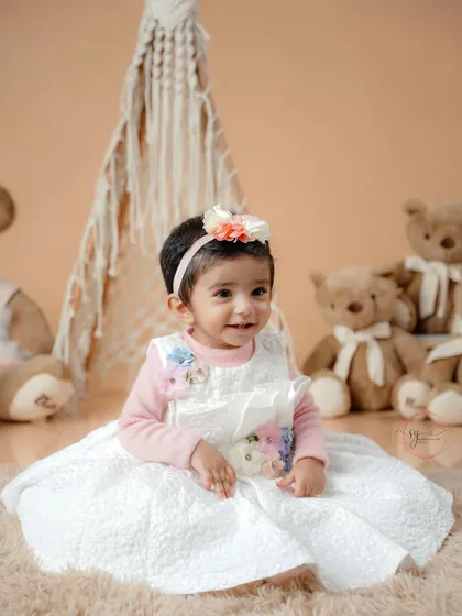A close-up shot highlighting the beautiful details of the baby's dress and the soft, gentle expression of the birthday girl.