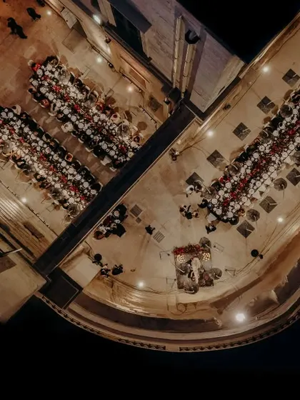 A stunning top-down drone shot of the elegant sit-down dinner in Malta, capturing the beautiful symmetry of the table settings against the dark night.