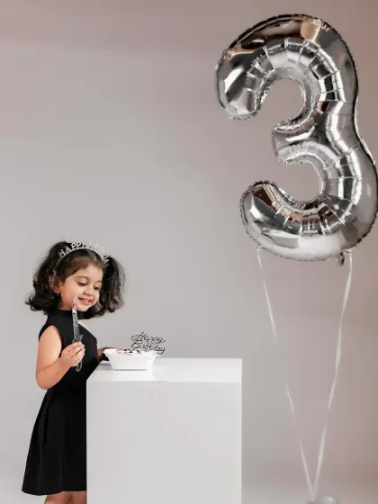 A little princess enjoying her birthday treat. This shot captures the quiet joy of a milestone celebration.