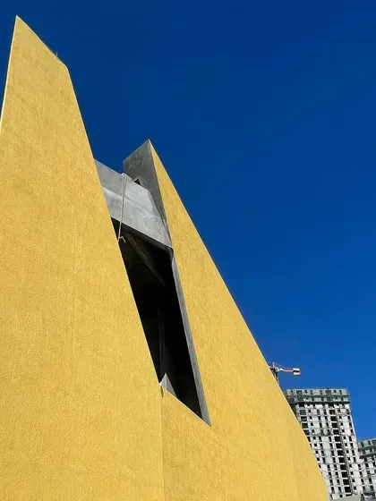 A detail of the sharp peak of the brigade utopia facade against a clear blue sky.