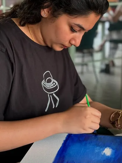 A participant deeply focused on her painting of a night sky. The concentration in the room is always palpable.
