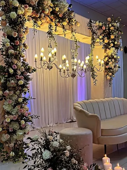 An intimate and elegant setup for a Roka ceremony. The decor features a beautiful floral arch, a classic chandelier, and candlelights for a warm and romantic feel.