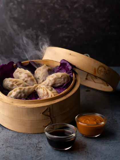 Steamed momos in a traditional bamboo steamer, with steam gently rising. This shot captures the freshness and authenticity of the dish, making it look like it just came out of the kitchen.