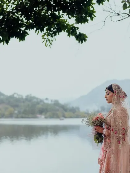 A serene bridal portrait by the lake, the bride holding a bouquet, her thoughtful expression reflecting the beauty of the natural surroundings.