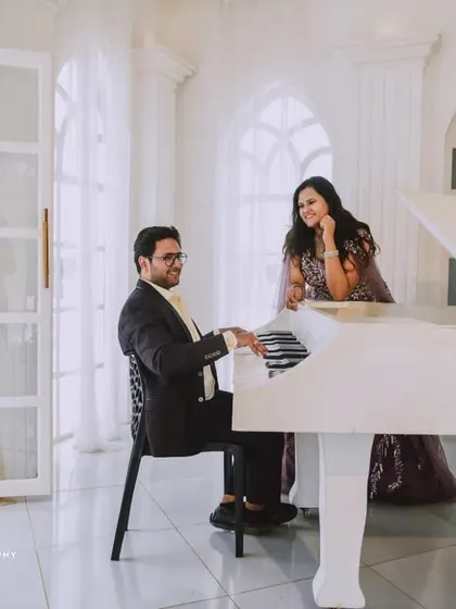 An all-white, classic European-style studio sets the stage for pure romance. The grand piano and crystal chandelier add a touch of musical elegance to this couple's pre-wedding photos.
