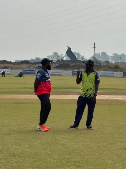 A candid moment between coaches on the field during a break in play. Sharing knowledge and experience is part of the game.