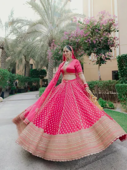 A vibrant action shot of the bride, Akanksha, twirling in her hot pink Sabyasachi lehenga in Abu Dhabi. The movement and color are simply breathtaking.