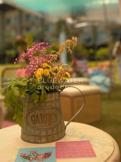 A rustic watering can serves as a vase for a wildflower arrangement, a charming detail for a garden party.