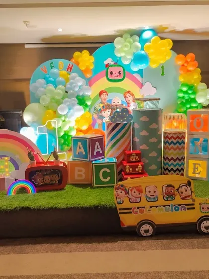 A complete Cocomelon stage setup with a green turf floor, rainbow props, and character cutouts for an immersive experience.