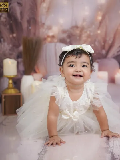 A simple and elegant portrait of a little girl in a beautiful white dress, crawling towards the camera with a happy smile.