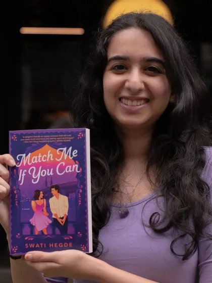 I'm a published author! Holding up my debut, "Match Me If You Can." It's a dream to see it on shelves next to authors like Emily Henry.