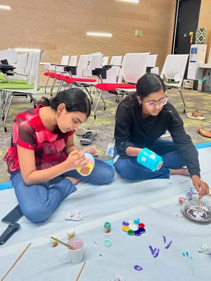 Two participants sitting on the floor, deeply focused on painting their vases. We create a comfortable and relaxed atmosphere for our art sessions.