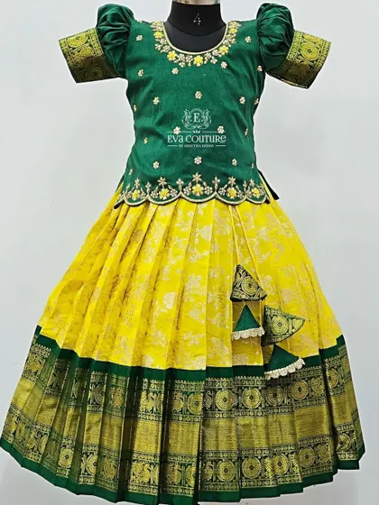 A bright and cheerful pattu pavadai in yellow and green. The green blouse has simple floral embroidery, and the yellow Banarasi skirt is finished with a wide green and gold border.