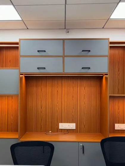Office workstations with ample overhead storage, finished in a modern grey and wood-grain laminate. The under-cabinet lighting provides excellent task lighting.