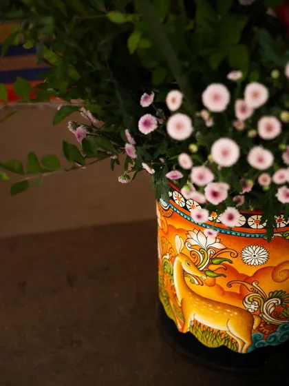 A close-up of a hand-painted vase featuring a traditional Kalamkari-style deer motif. Using such artisanal pieces ensures that every corner of an event is filled with art and story.