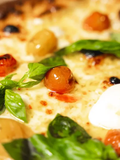 A macro shot of the toppings on our delivery-optimized pizza. The confit cherry tomatoes and fresh basil still look and taste vibrant after the journey.