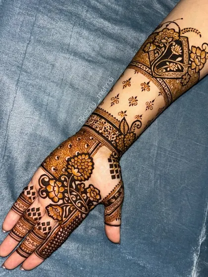 A gorgeous floral design that extends up the arm. The use of negative space with scattered motifs on the forearm contrasts beautifully with the denser patterns on the palm.
