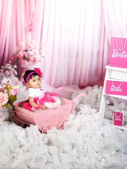 Pretty in pink and ready for her close-up. This little girl sits in her pink pram, the star of her very own Barbie-themed fairytale.