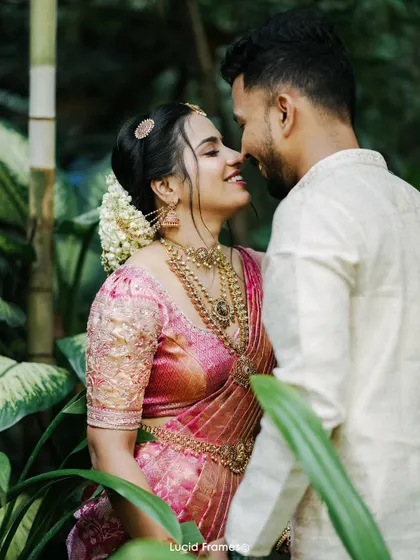 A romantic portrait of the couple surrounded by lush greenery, capturing the feel of a tropical Kerala wedding.
