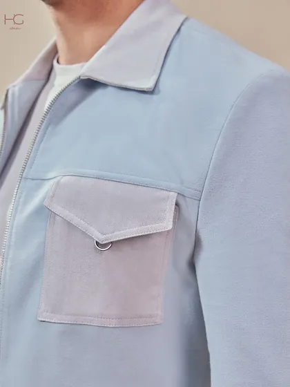 A close-up on the pocket detail of the light blue shacket, showcasing the mix of textures and hardware that gives it a unique, standout quality.