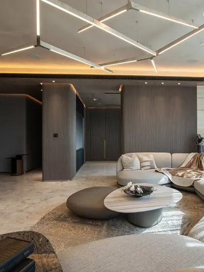 A different angle of the Lodha World View living room, showcasing the custom geometric lighting fixture that follows the curve of the ceiling. The design creates a perfect balance of opulence and elegance, embodying the family’s refined taste.