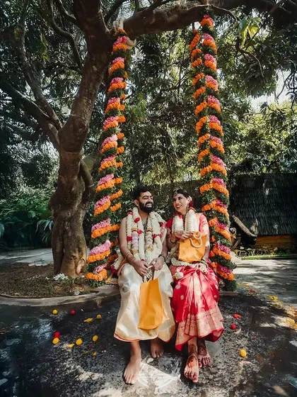A couple seated on a traditional marigold-wrapped swing, a classic element of South Indian weddings.