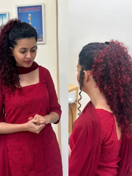 A different view of the fiery red curls, styled in a high ponytail to showcase the volume and the beautiful color gradient.