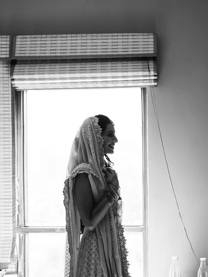 A beautiful black and white silhouette of the bride as she gets ready by the window.