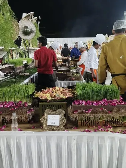 A view from behind the buffet, showing my team working at a fully decorated salad counter with wheatgrass boxes and fresh flower arrangements.