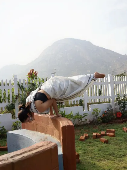 Mayurasana (Peacock Pose) on a ledge, a powerful demonstration of arm and core strength.