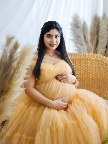 A seated portrait in a lovely yellow-gold ruffled gown. The boho studio setting provides a warm and inviting backdrop.