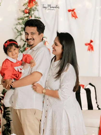 A beautiful family of three enjoying the festive spirit. The little girl's bright red dress and happy smile are the perfect centerpiece for this holiday portrait.