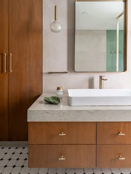 A detail of the primary bathroom vanity. The warm wood tones, marble countertop, and classic hardware create a timeless and functional space that feels both luxurious and approachable.