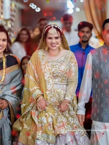 A radiant bride makes her entrance, surrounded by family. Her glowing outfit and happy smile are the center of this beautiful celebratory moment.
