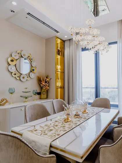 Another view of the elegant dining space, featuring a beautiful sideboard and a unique mirror made of layered golden discs.