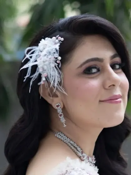 A close-up of the wavy hairstyle and feather accessory. I pay close attention to detail to ensure every element of the look is perfectly placed and secure.